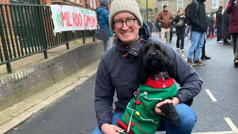 A man and a dog dressed in a Christmas cardigan