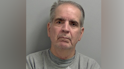A police mugshot of Robert Alexander in a grey prison sweatshirt
