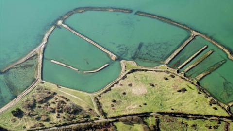 An aerial view of Langstone Harbour, an area of land by the sea with several strips of land extending into the water