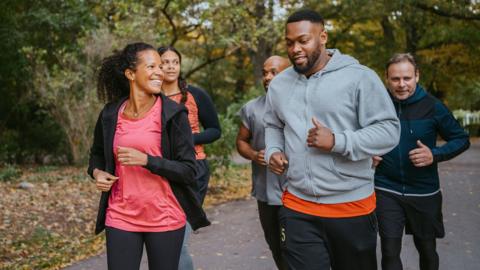 Male and female friends jogging on road in park 