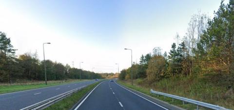 The A19 road, a dual carriageway with two lanes either side of a narrow central reservation. There are trees and lampposts bordering the road. In the distance, two cars are travelling in opposite directions.