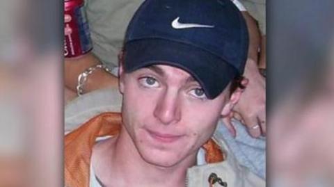 A headshot image of Luke Durbin. A young man wearing a navy Nike baseball cap. He is smiling and looking directly into the camera. 