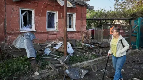 An elderly Ukrainian woman walks past her damaged home following a combined overnight attack in Kharkiv, Ukraine, 02 June 2025