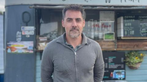 A man is standing in front of a coffee cart