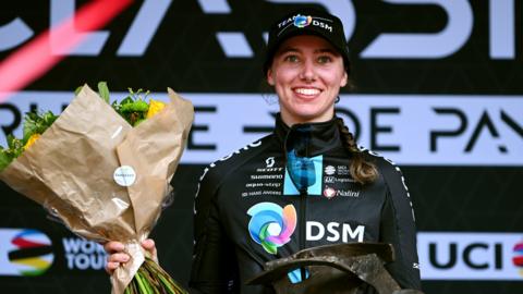 British cyclist Pfeiffer Georgi smiles as she holds up the trophy for winning Classic Brugge-De Panne on the podium