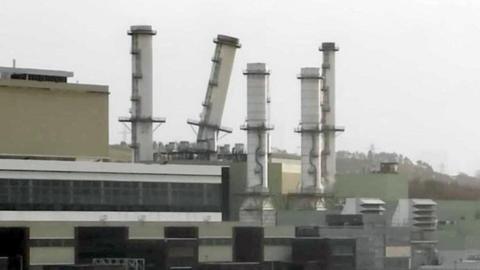 The picture shows five chimney stacks at a power station, one of which is leaning at an angle.