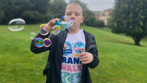 Harry Studley blowing bubbles outside