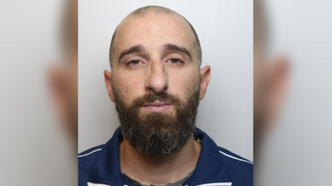 Police handout of Sorrenti - balding with mostly shaved head, but bushier brown beard, wearing a dark blue top.