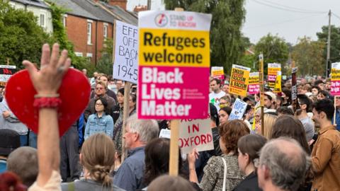 A large crowd of people holding up anti-racism banners