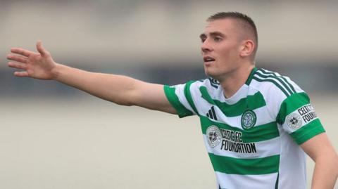 Kyle Ure puts is arm out offering some instructions to team-mates during a game for Celtic