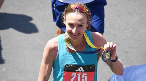 Paul Radcliffe smiles as she shows off her medal for completing the Boston Marathon