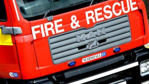 the words fire and rescue are spelled out along the front of a red Marhsall SV fire engine, 