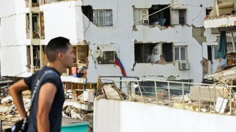 A man walks past damaged buildings in La Guaira, Venezuela
