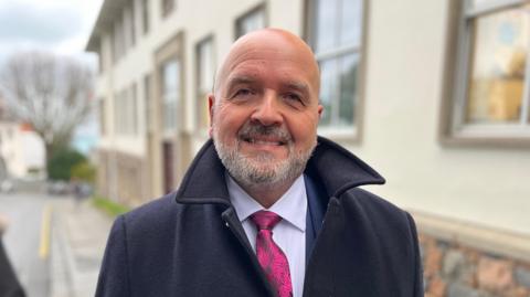 Deputy Jonathan Le Tocq pictured outside Guernsey's Royal Court wearing a suit, tie and winter jacket. 