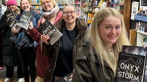 Young women queue up to buy copies of Onyx Storm in Waterstones in Warrington, holding up their books