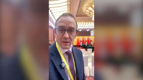 A man, Chris Mason, looking to camera in the Great Hall of the People