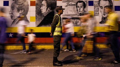 A member of the Venezuelan National Guard keeps watch as people cross the Simon Bolivar International Bridge