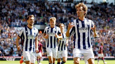 Isaac Price (right) holds his hands up in celebration as team-mates run behind him