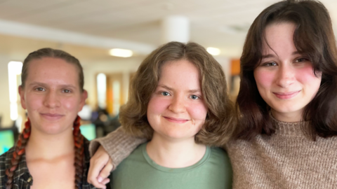 Coleg y Cymoedd students Olwen, Elinor and Maddie smiling at the camera in the college library 