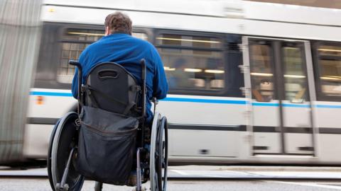 Man in wheelchair with spinal cord injury trying to catch a local bus