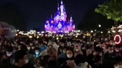 Mask wearing crowds in front of iconic Disney castle