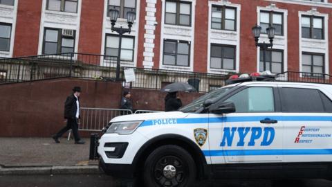 A New York police vehicle sits outside of the synagogue where an illegal hidden tunnel was found below it.