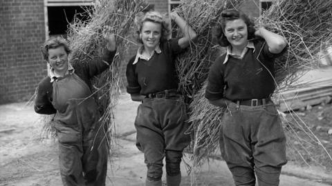 Land Girls carrying bundles of straw in 1941.