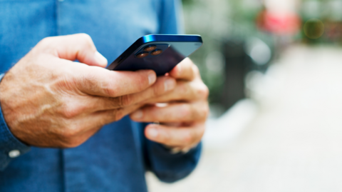 Image shows hands texting on a mobile phone