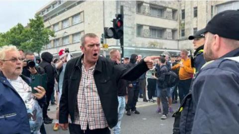 Plymouth city centre protest with a man pointing at another man