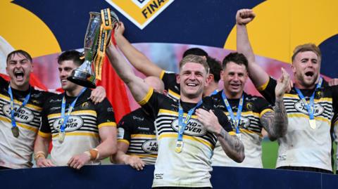 Liam Harris lifting the 1895 Cup alongside team-mates