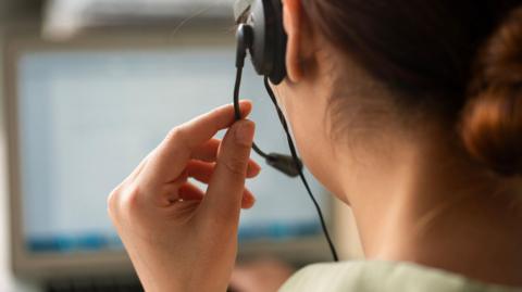 A woman wearing a phone headset at a call centre
