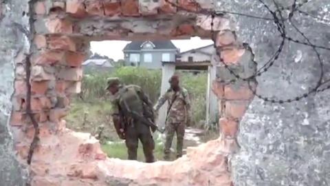 Soldiers seen through a hole in a wall