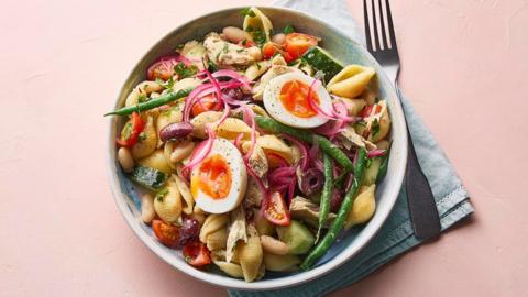 A bowl with pasta, sliced boiled eggs, mackerel, tomatoes and beans