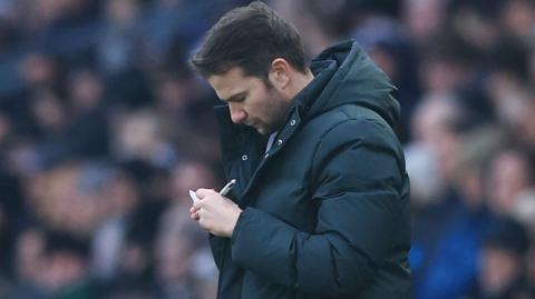 Tom Cleverley takes notes on the touchline