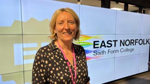 Dr Catherine Richards, standing in front of an East Norfolk Sixth Form College logo