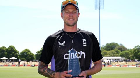 England bowler Brydon Carse holds up the player of the match trophy after the first Test win over New Zealand