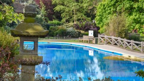 An outdoor paddling pool surrounded by trees