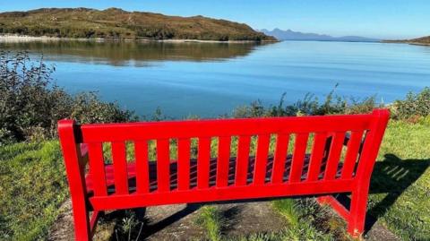 Red bench overlooking view of the Isle of Rum 