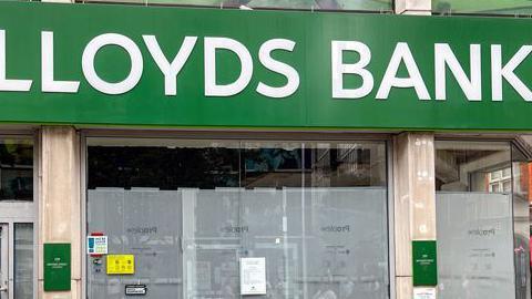 A former Lloyds Bank branch now closed and boarded up; the typical green Lloyds signage is still visible, but the windows are obscured by a grey covering. 