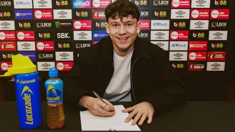 Alex Toth signs a contract at Bournemouth and smiles