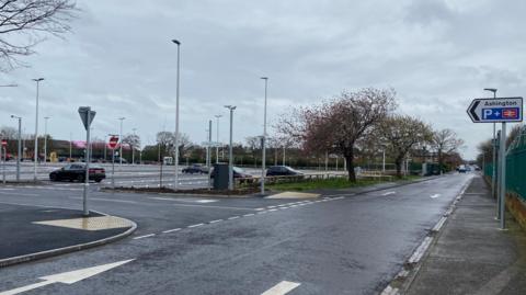 A large station carpark with lots of lights and a sign saying Ashington station.