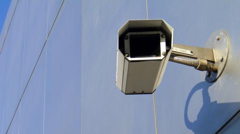 A close-up image of a CCTV camera on the side of a building.
