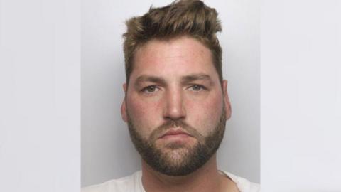 A mugshot of Michael Burgess, who has brown hair, brown eyes and a beard 