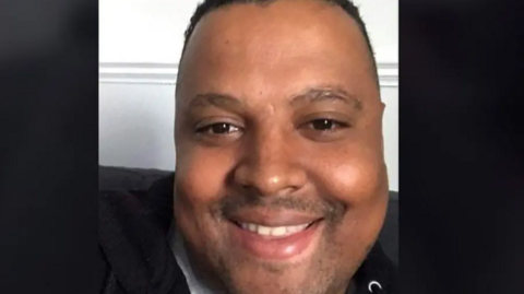 A man looks at the camera smiling.