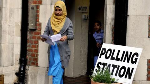 Woman leaves with her son after casting her vote at a polling station at Christchurch Primary School in Brick Lane,