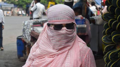 A woman covers her face while walking on the street during the heatwave in Kolkata, India, on April 20, 2025.