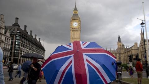 A union jack umbrella in front of the Palace of Westminster