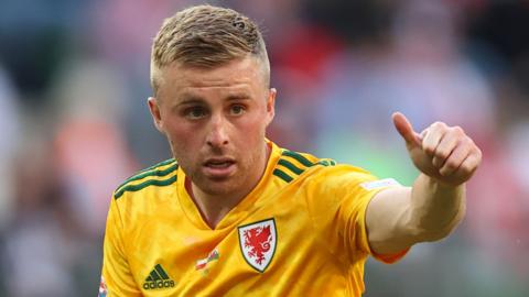 Joe Morrell puts a 'thumbs-up' while playing in a yellow Wales jersey