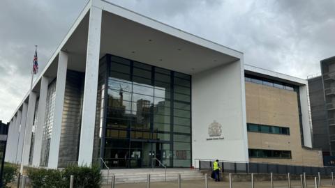 The Ipswich Crown Court building in Ipswich. The concrete and glass frontage can be seen, as can the emblem of the court on one of the walls.
