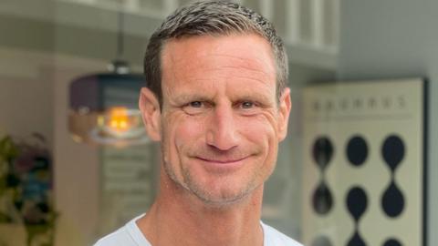 Steve Wyatt smiling to camera in front of his shop